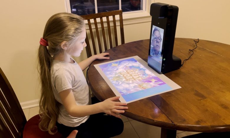 A child sits at a table and looking at a game projected from an Amazon Glow